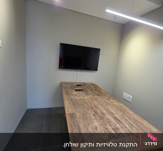 חדר ישיבות עם שולחן עץ ומסך טלוויזיה